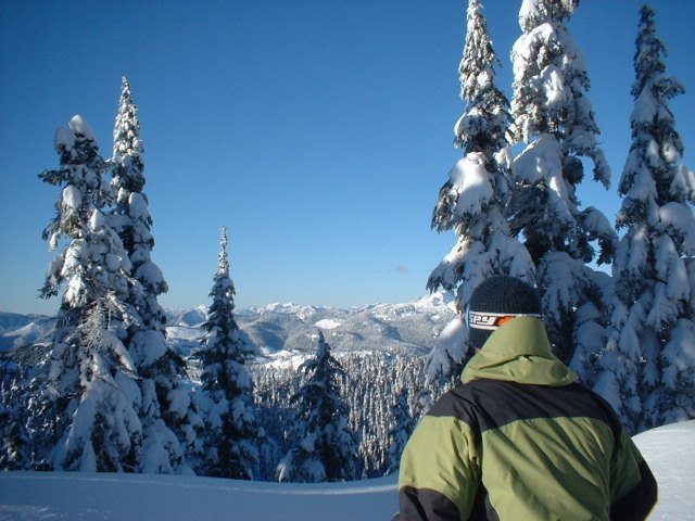 A snowshoer looking out over the snow-covered peaks and forests of Hemlock Valley